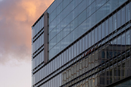 Modern glass office building facade with sky cloud reflection forming a bold pattern and clean architecture texture for corporate urban background