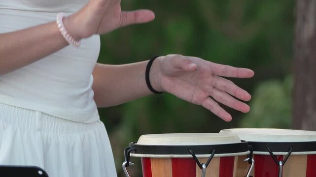 Bongo drums, playing, hands, young woman plays bongo drums outdoors creating rhythmic music