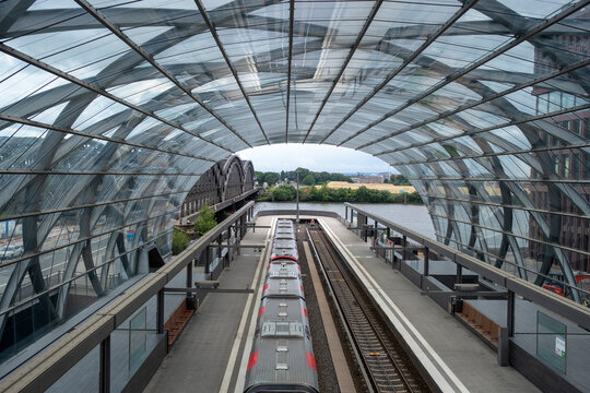 Glass roofed rail station with train tracks and platform creating modern urban architecture lines for transport travel in Hamburg Germany