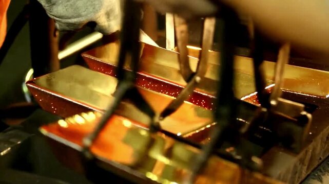 Gold smelting process and casting molten gold into bars.  glowing, molten gold being poured or treated in a high-temperature furnace environment. 