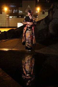 Woman in furisode kimono standing at night with reflection on Seijin no Hi