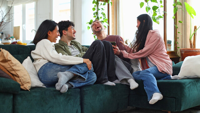 Friends laughing together, enjoying time on sofa at home