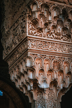 View of intricately carved stone pillar adorned with Moorish script and geometric patterns casting shadows, a showcase of Alhambra's architectural splendor, Alhambra, Andalucia, Spain.