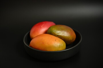 Top view of fresh mangoes on dark background, symbol of clean eating and choosing whole organic fruits over sugary drinks and concentrates
