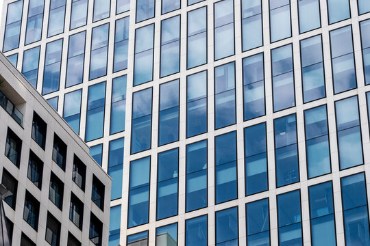 Glass office architecture facade in modern urban scene with windows reflections grid and perspective built as abstract background texture
