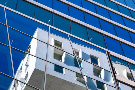 Blue glass office facade shows architecture windows and reflections in modern urban geometry creating a clean abstract background