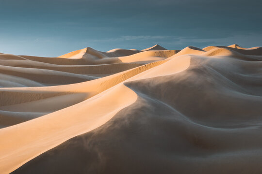 View of rippling sand dunes sculpted by wind under a serene sky create a mesmerizing landscape, casting long shadows and highlighting textures, Senek, Mangystau Region, Kazakhstan.