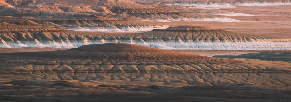 View of layered sandstone formations with white mineral deposits create a surreal, otherworldly landscape in the desert, Kyzylkup, Mangystau Region, Kazakhstan.
