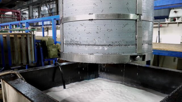 Industrial machinery processing foamy white liquid in large metal tank