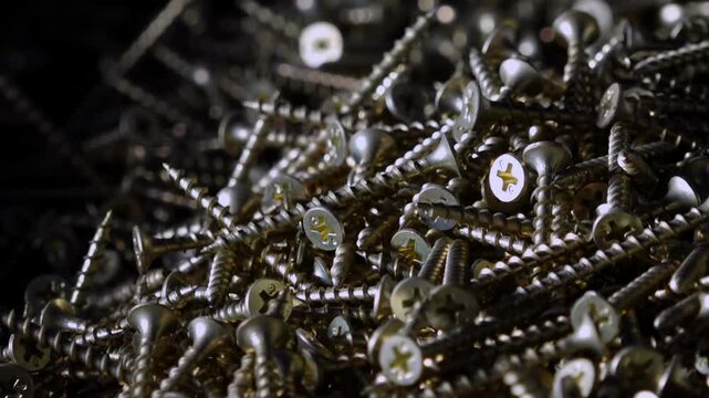 Close-up shot of a pile of shiny metal wood screws illuminated by dramatic lighting.