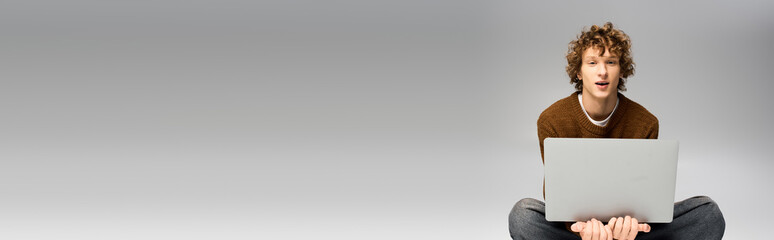 Stylish young man enjoying leisure time while using a laptop in a modern setting