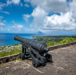 An ancient Cannon among the ruins of the Brimstone Hill Frotress in Saint Kitts, Saint Kitts and Nevis. The island of island of Sint Eustatius in the background