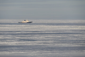 Powerful industrial icebreaker ship navigating through the thick frozen ice fields of the Baltic Sea during a harsh winter season. © Dmitri
