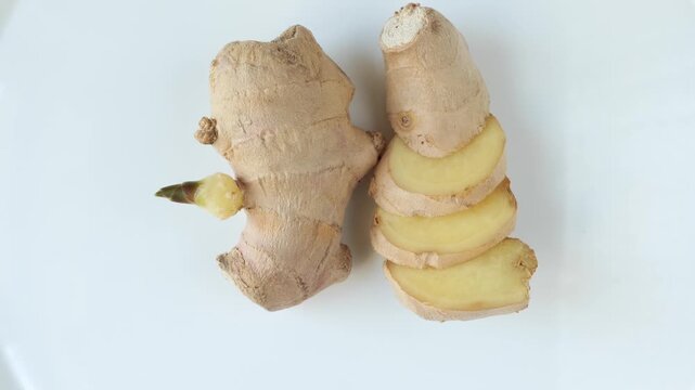 Sliced fresh ginger root rotating on white background.