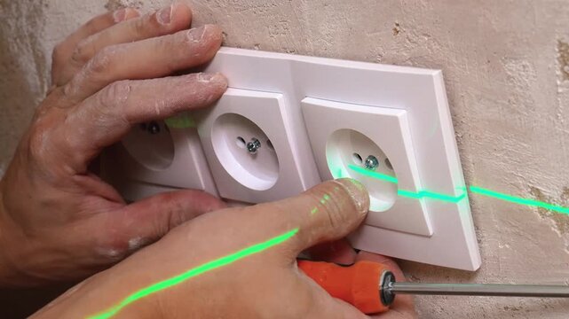 Using Laser Technology To Align Multiple Outlets Precisely During Installation Work. Employing Laser Level To Accurately Position Socket Covers Across Various Frames During Setup Process