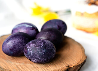 Dark purple Easter eggs on a natural wooden background. Minimal festive spring composition. Close-up. Selective focus.