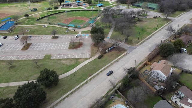 Recreation zone at Cravens Park near Nathan Lowe Rd displays ballfields, courts, pavilions, adjacent housing. Bright roofs, open turf, bare trees, clean pavement textures stand out, Arlington, TX