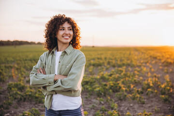 Young agronomist woman enjoying sunset in soybean field