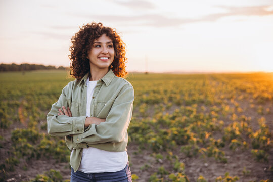 Young agronomist woman enjoying sunset in soybean field