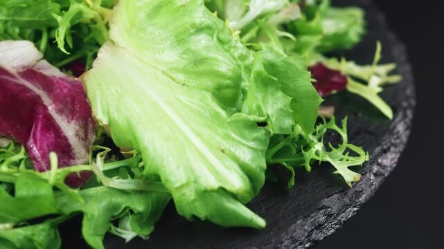 A mixture of healthy greens in a plate on a black background. Diet food.