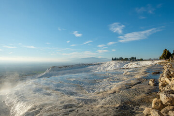 The white travertine terraces of Pamukkale, under a bright blue sky, located in Denizli