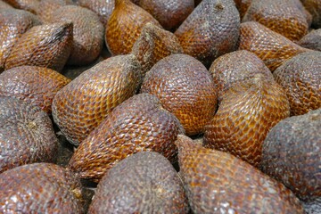 Close-up shot of a textured pile of salak fruit, also known as snake fruit, showcasing the brown, scaly skin and the unique form of the tropical delicacy, perfect for food and nature-themed 