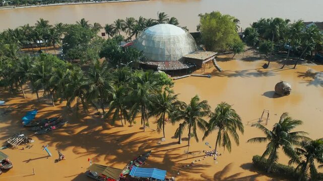 flooded city or town with buildings submerged in overflow water and mud, village underwater after heavy tropical rain and typhoon, consequences with dirt on the street, aerial drone view 4k