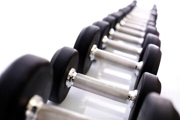 Obraz premium Row of black rubber hex dumbbells on a metal rack ready for workout