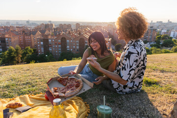 Diverse friends enjoying outdoor pizza picnic at sunset