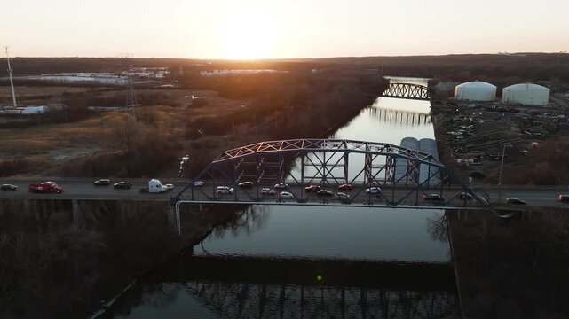 Aerial Shot Of Bridge With Heavy Traffic Crossing Canal During Sunset