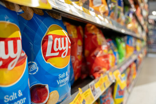 Lay's salt and vinegar chips displayed prominently in a grocery store aisle among various snack brands