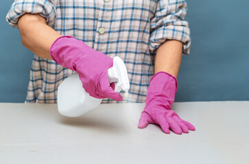 Person in casual clothes cleaning gray surface by spraying. House cleaning, hygiene and surface care