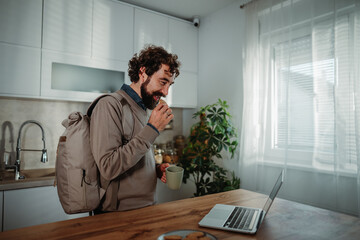 Fototapeta premium Man snacking and working from home in kitchen