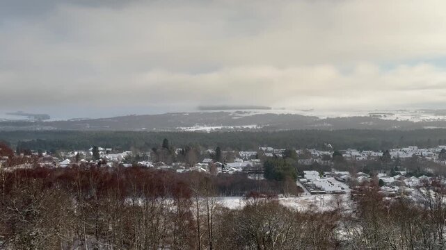 A view of a winter village. Grantown-on-Spey from above. Winter mountains and a snow-covered village in Scotland.