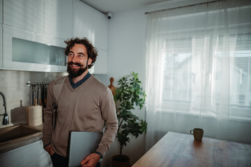 Fototapeta premium Professional man preparing for remote work in kitchen