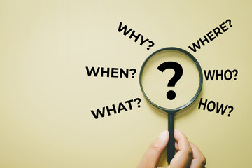 Problem solving and root cause analysis. Hand with lens zooming on question mark with 5W1H words. Concept of strategic planning, research, critical thinking, and finding solution.,copyspace.