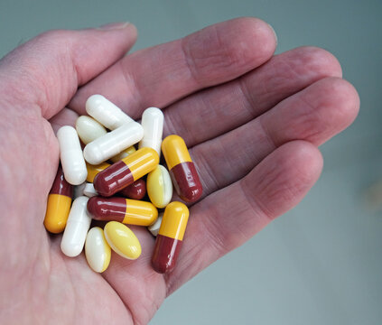 White adult males hand or palm holding a variety of pills, capsules and tablets. Health, Illness prevention and cure or drug misuse and addiction. 