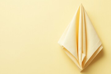 Fototapeta premium Elegant mustard-colored napkin beautifully folded on a soft yellow background radiating warmth and charm
