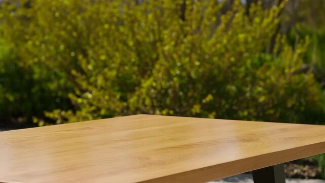 Wooden tabletop background with bokeh greenery and bright sunlight for product showcase or outdoor marketing