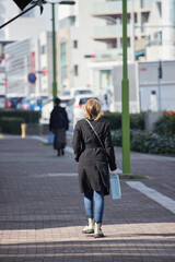 冬の朝の都市の繁華街で歩く一人の外国人女性の姿