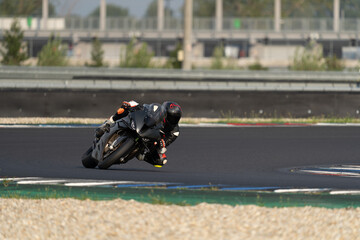 Professional motorcycle racer on a black sport bike leaning extremely low into a sharp turn on a racetrack.