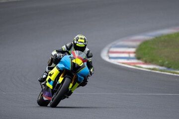 Professional motorcyclist in racing gear leaning deep into a corner on a blue and yellow sport bike on a racetrack. © Jakub Sisulak