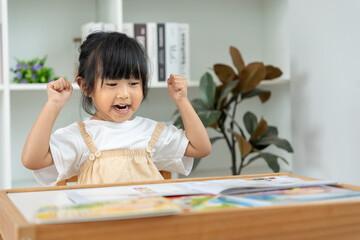 Naklejka premium Happy Asian children relax read book at home. daughter and reading a story. learn development, childcare, laughing, education, storytelling, practice, imagine, reduce addiction mobile phone