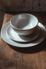 Handcrafted Ceramic Dinnerware Stack on Rustic Wood, Illuminated by Warm Natural Light.