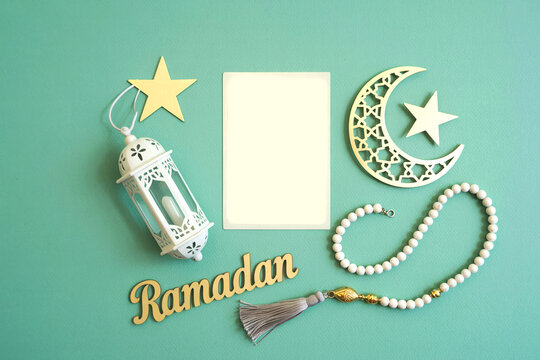 Ramadan greeting card mockup with white blank paper, lantern, crescent moon, and prayer beads on teal background for Islamic holiday invitation
