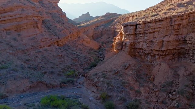 Aerial view captures vast canyon and unique rock formations in Kyrgyzstan. Arid landscape features dirt road and serene outdoor scene under a clear sky.