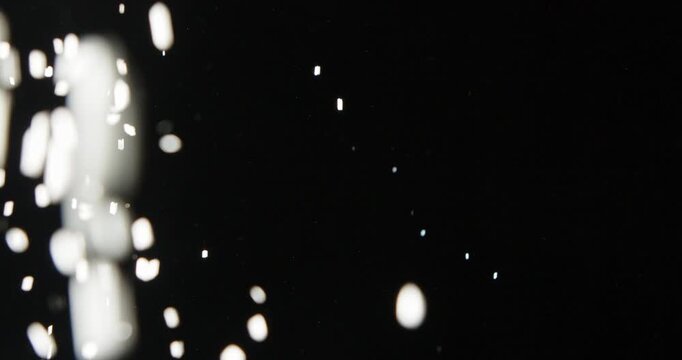 Tiny snow or dust randomly flying in the smoky air, empty space template for objects advertisement. Many dust particles cloud of white powder in low light on empty dark black contrast background.