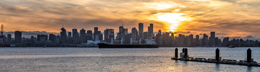 Winter sunset over Vancouver downtown with cargo ship on the water in front