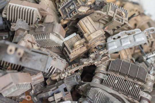 Heap of automotive scrap metal including old alternators and starter motors ready for recycling.
