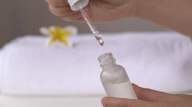 Cosmetic serum dropper above glass bottle in spa setting with woman hand dispensing oil for skincare formulation and beauty treatment concept for wellness branding and cosmetic product marketing